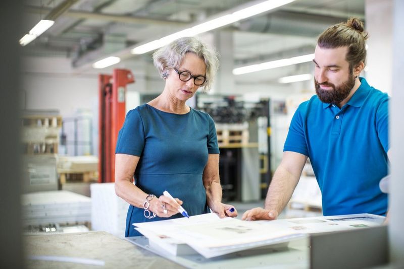 Coworkers examinging printouts at printing plant